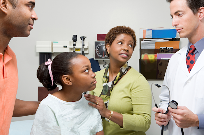 child speaking to doctor with family